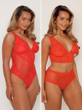 Woman wearing a red lace lingerie set on a plain background