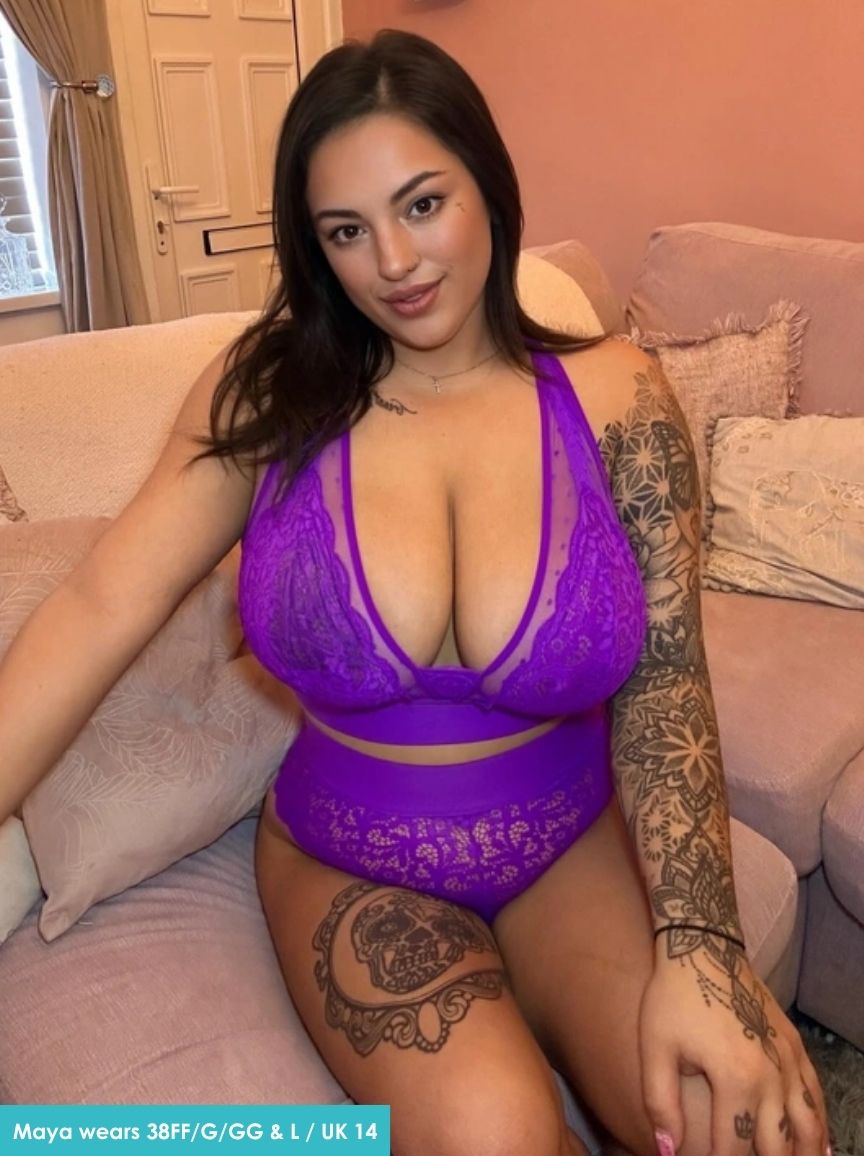 Woman wearing a purple lace lingerie set sitting on a couch.