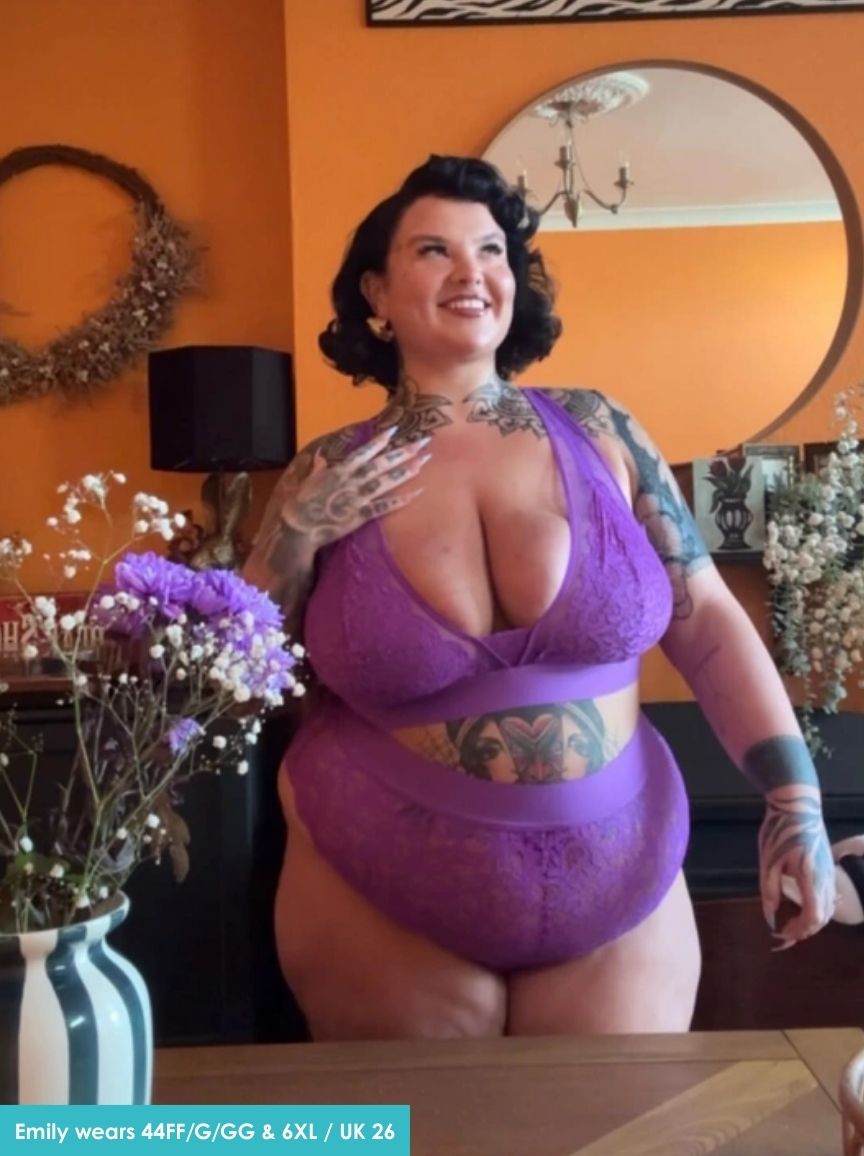 Woman wearing a purple lingerie set in a room with orange walls and decorative elements.