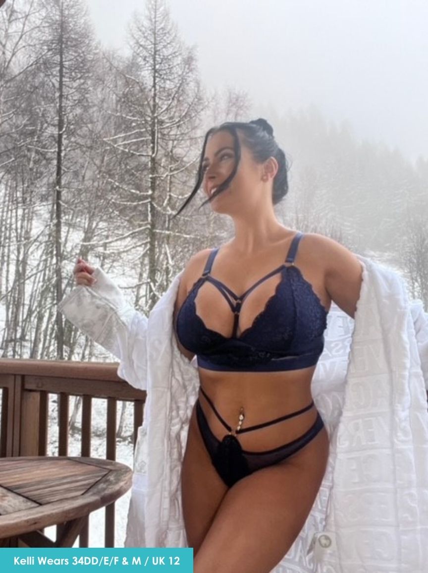 Woman in a blue bra and black underwear standing outdoors in a snowy landscape.