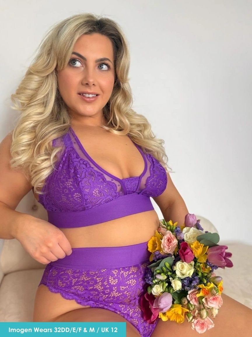 Woman wearing a purple lace lingerie set holding a bouquet of flowers.