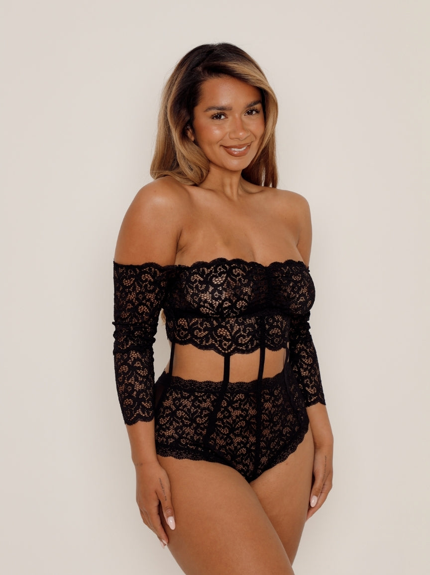 Woman wearing a black lace outfit against a plain background