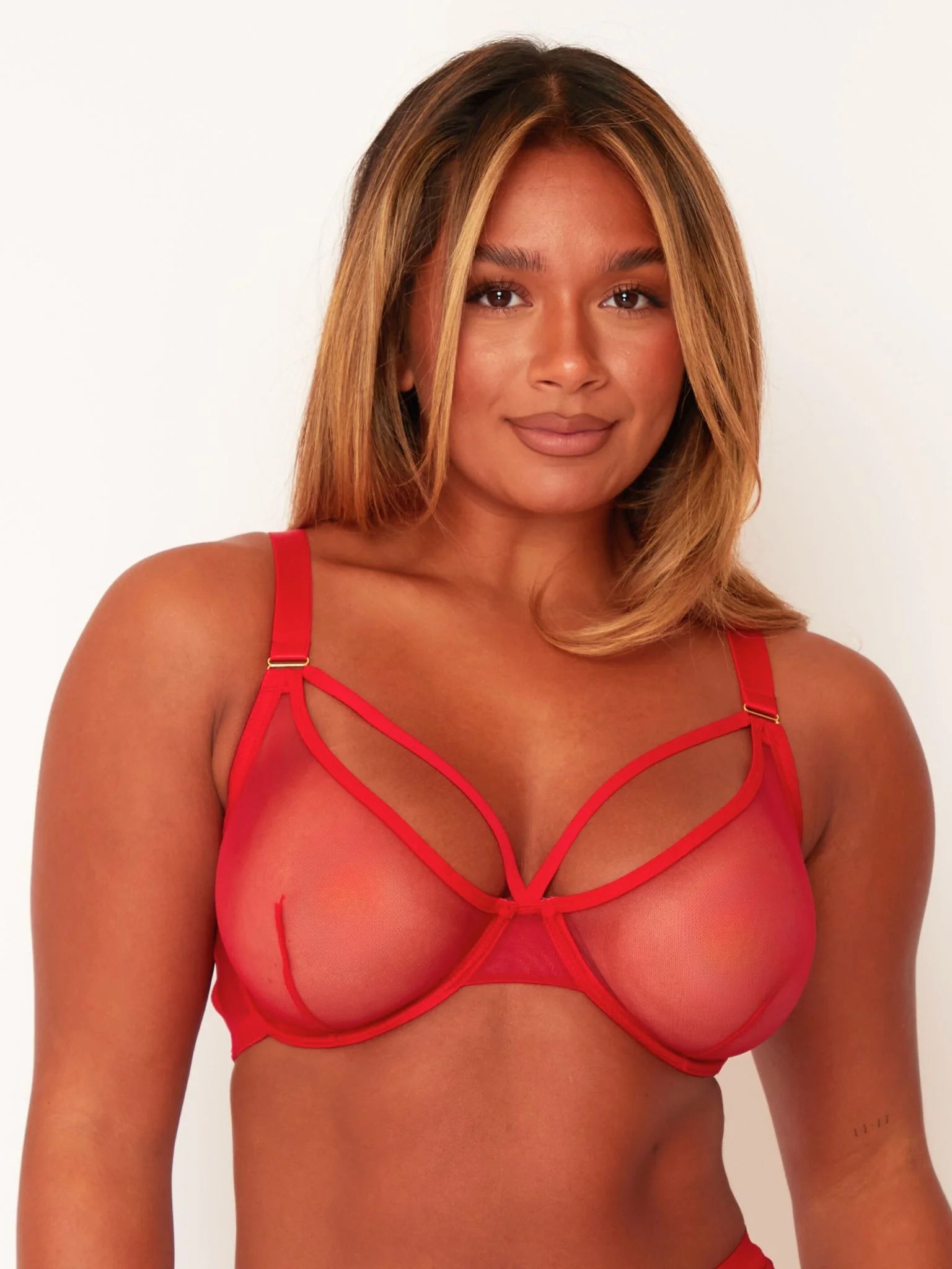 Woman wearing a red strappy bra against a white background